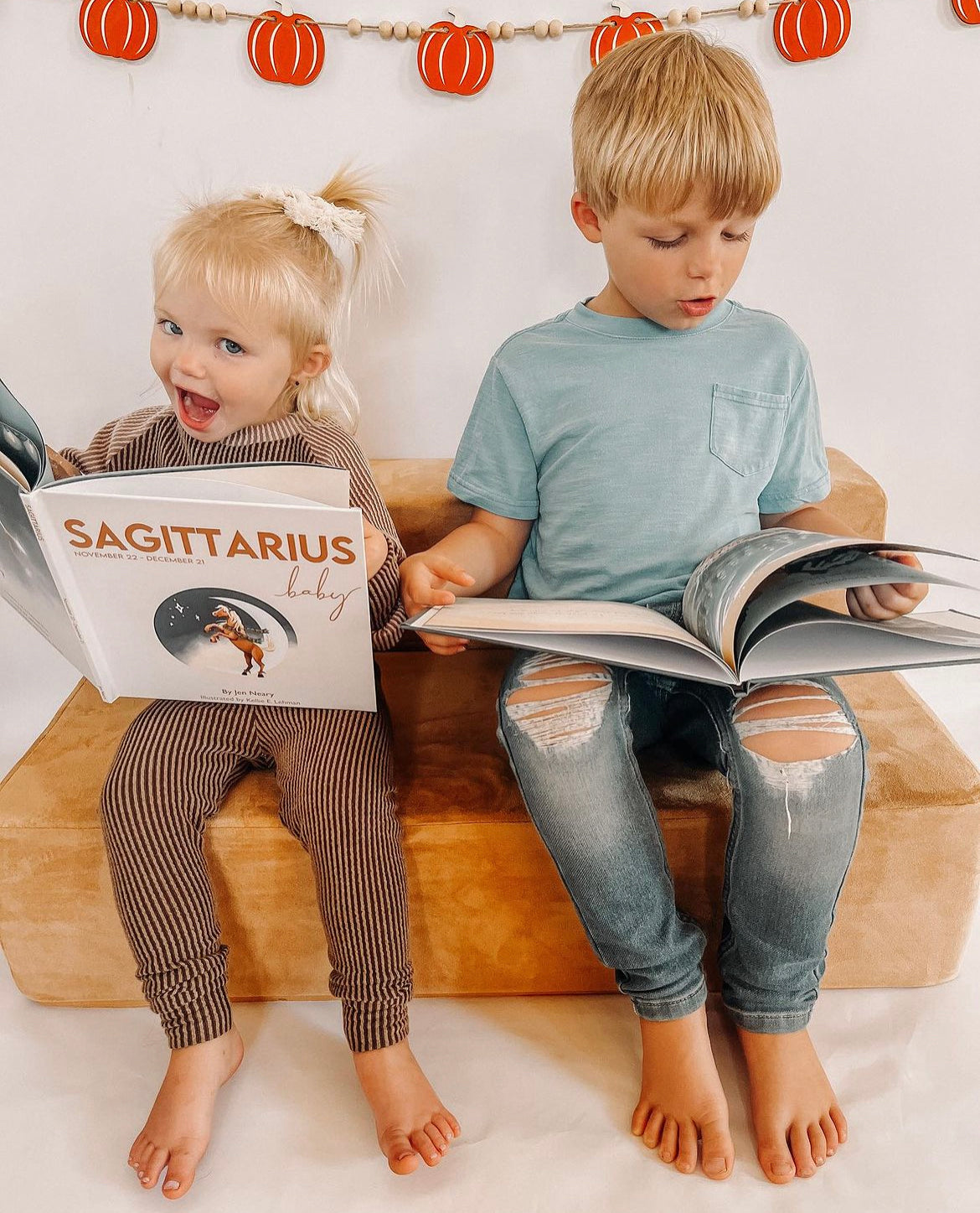 two kids holding the sagittarius baby zodiac book and the capricorn baby zodiac book by Jen Neary